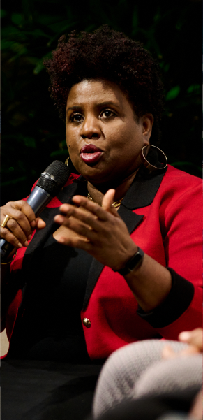 BEC leader in red speaking on a panel with a microphone